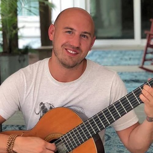 Jonathan Richter smiling playing classical guitar