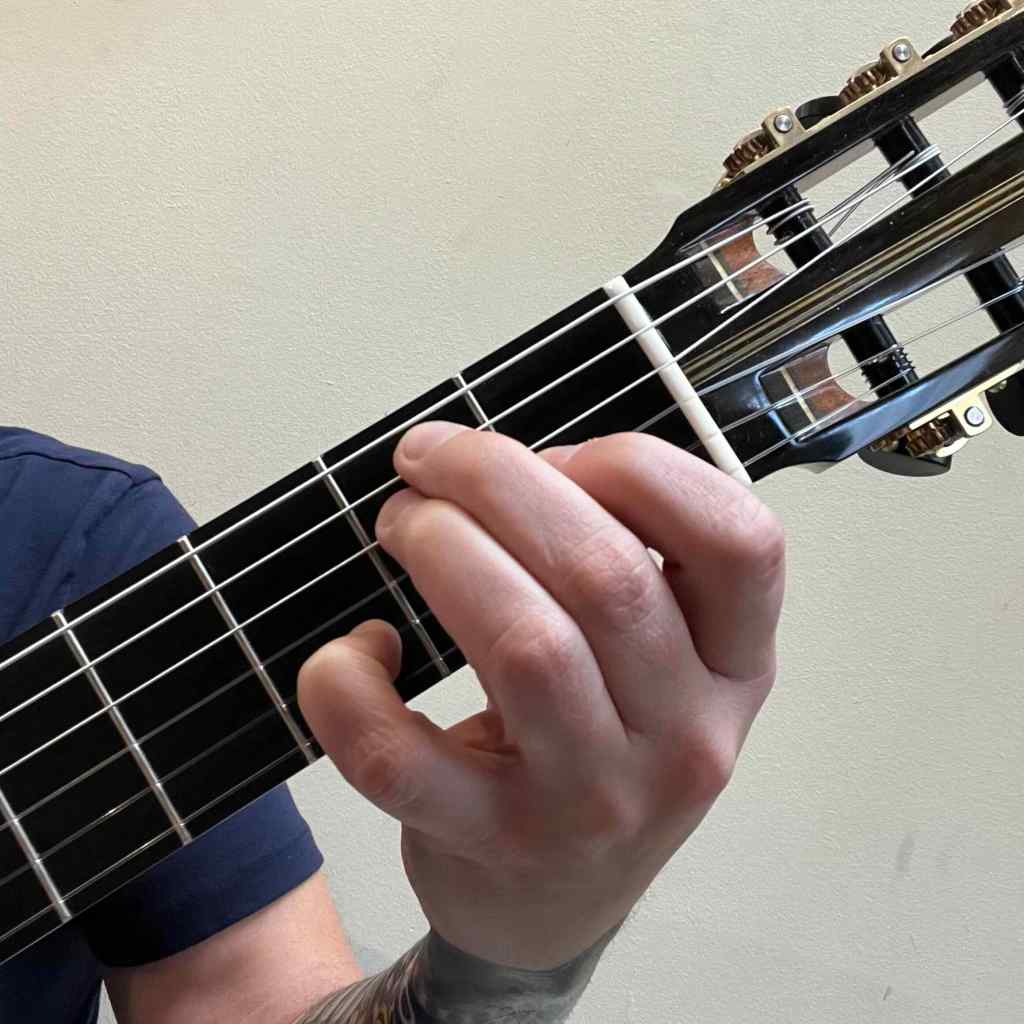 Jonathan Richter playing E7 guitar chord with pinky on string 2 on a classical guitar