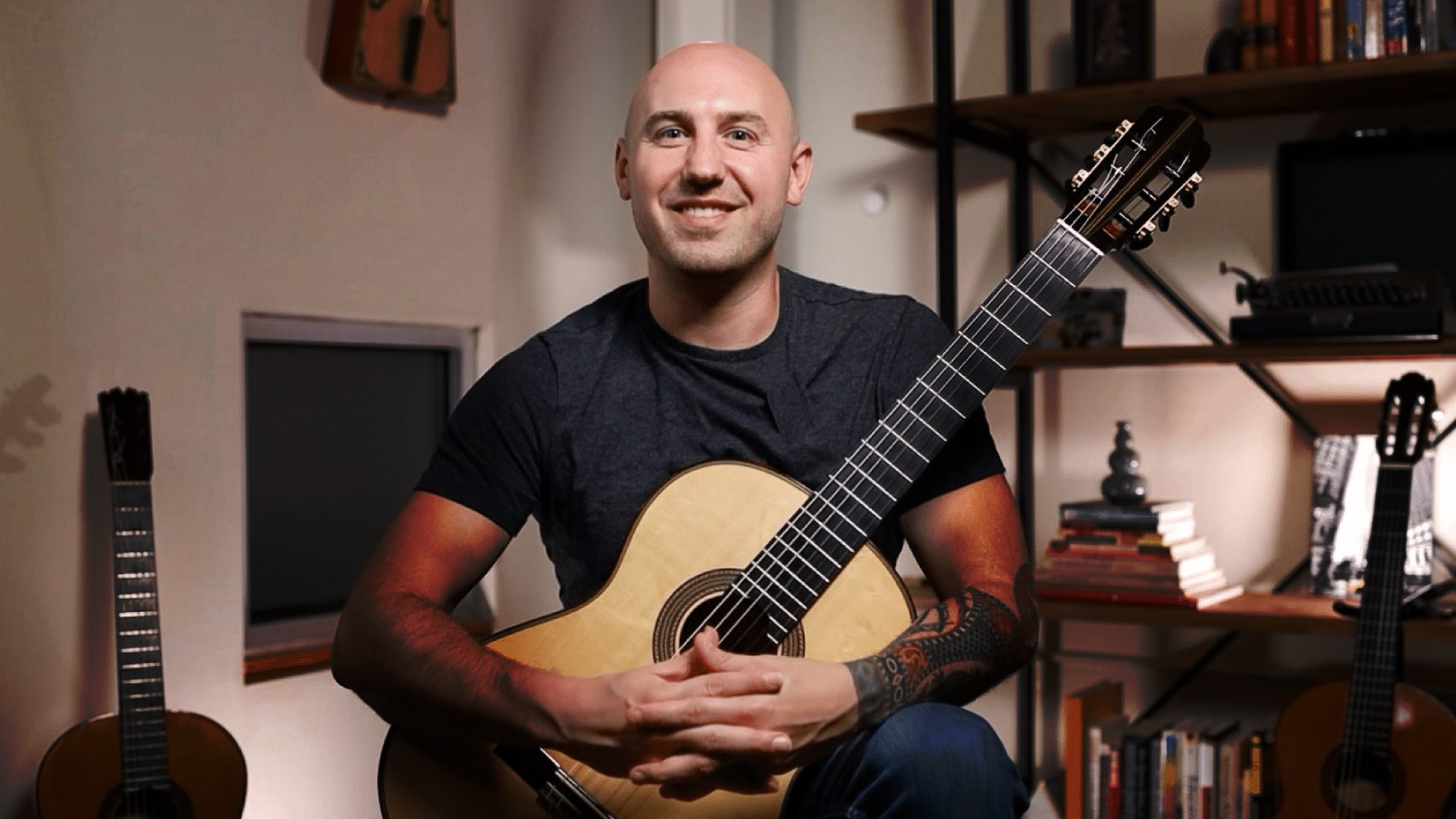 Jonathan Richter holding spruce top classical guitar smiling at camera in his home studio in Atlanta