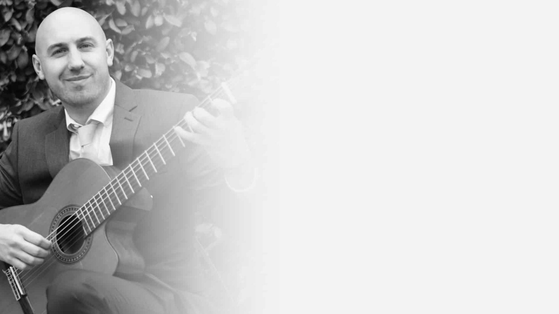 Jonathan Richter smiling playing guitar black and white