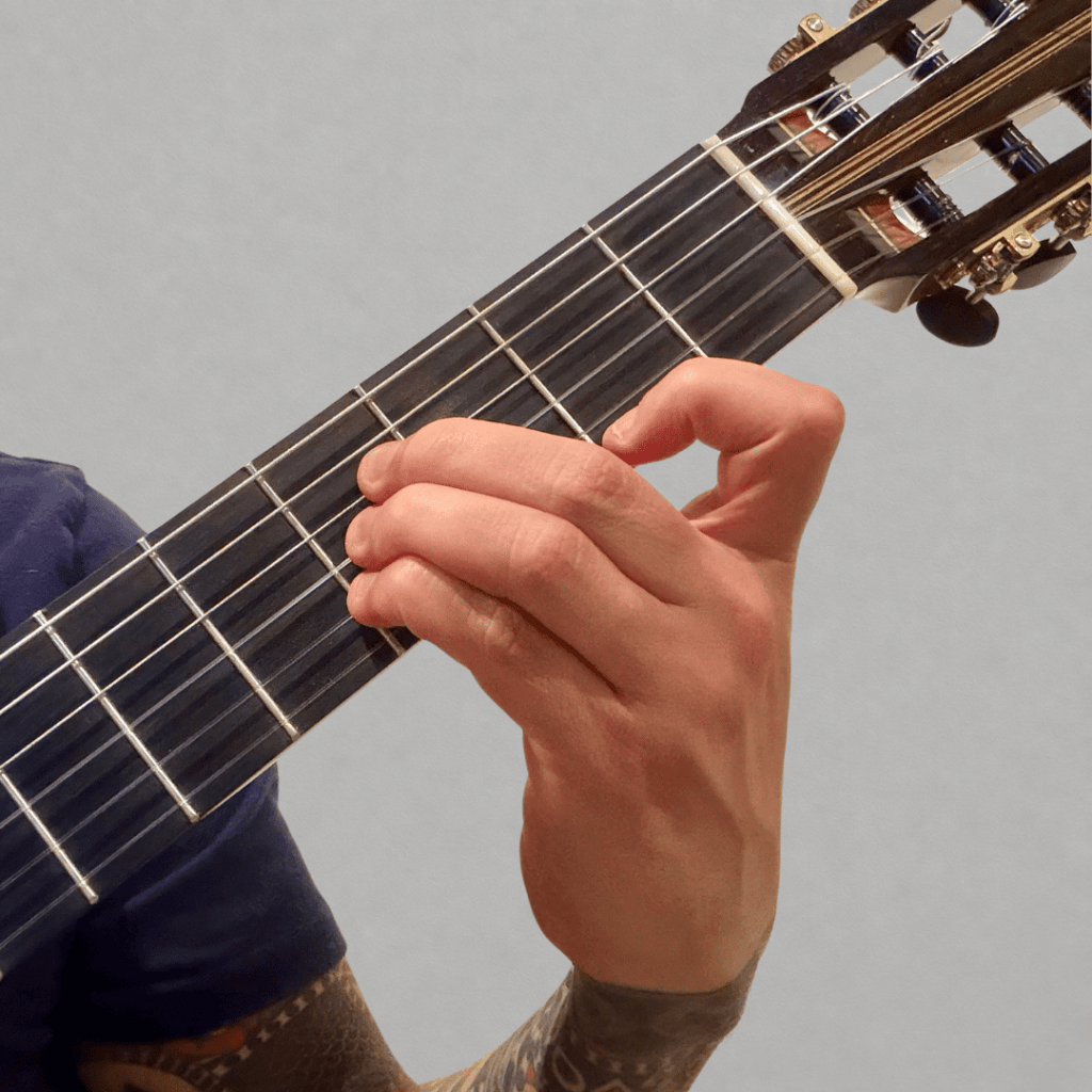 hand playing the B major chord shape on classical guitar with no barre, beginner-friendly